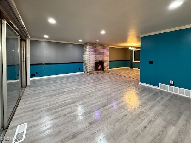 unfurnished living room featuring hardwood / wood-style floors, ornamental molding, and a brick fireplace