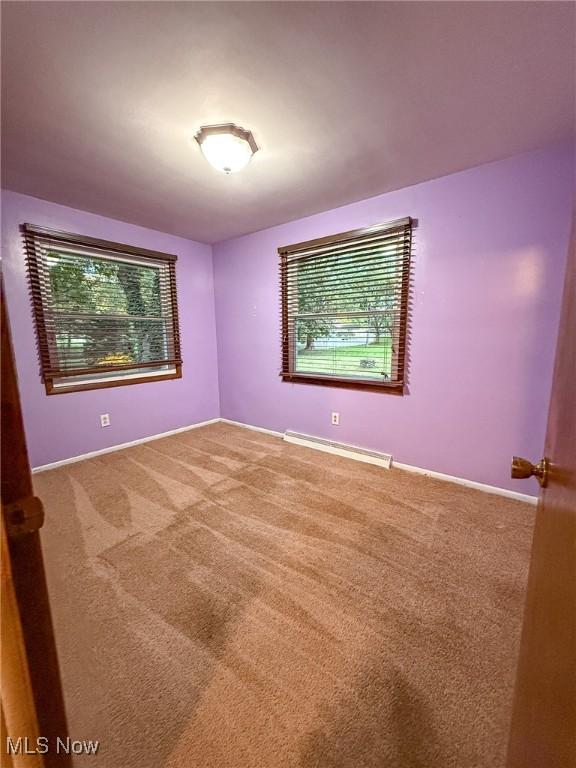 carpeted empty room with a baseboard radiator