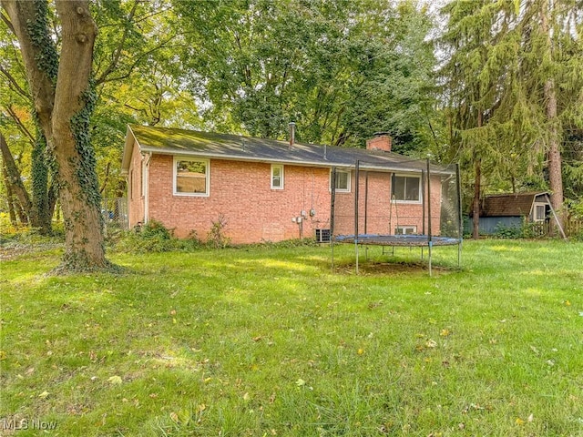 back of property featuring a lawn and a trampoline