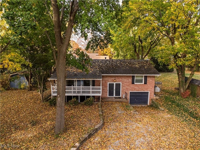 back of property featuring a wooden deck, a storage unit, and a garage