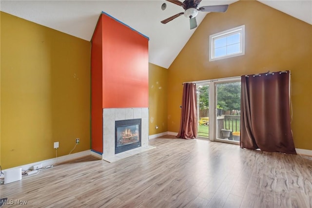 unfurnished living room featuring ceiling fan, a fireplace, high vaulted ceiling, and light wood-type flooring