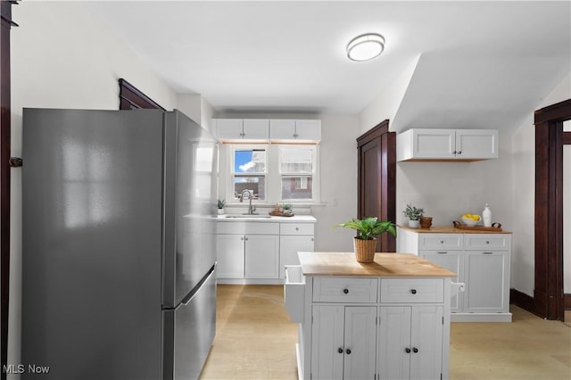 kitchen featuring stainless steel fridge, white cabinetry, sink, and light hardwood / wood-style floors