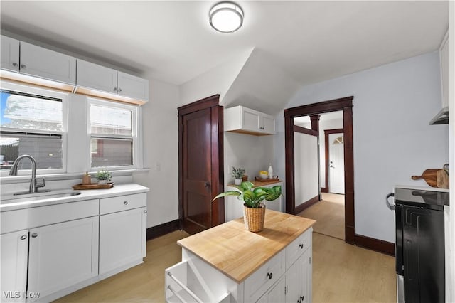 kitchen featuring wood counters, white cabinetry, sink, and light wood-type flooring