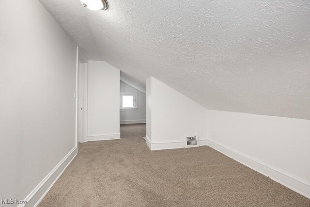 bonus room with carpet floors, a textured ceiling, and vaulted ceiling