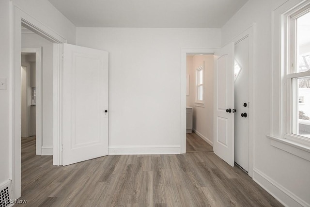 unfurnished bedroom with multiple windows and wood-type flooring