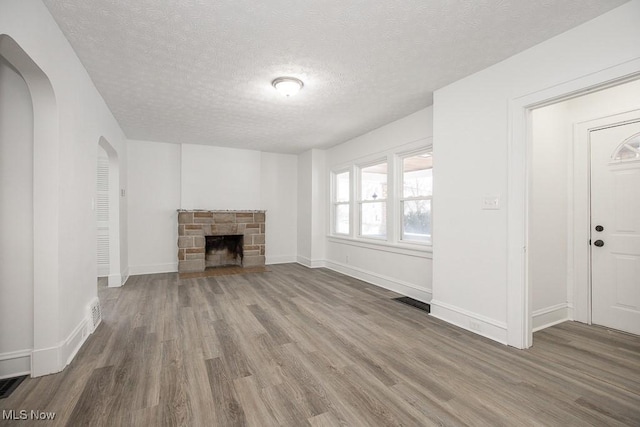 unfurnished living room with hardwood / wood-style flooring, a fireplace, and a textured ceiling