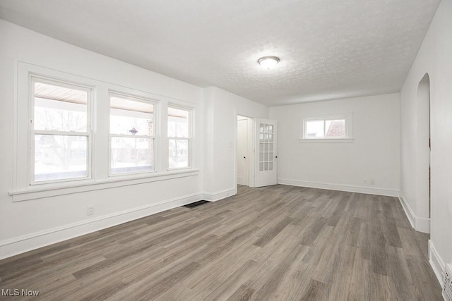 spare room with a textured ceiling and dark hardwood / wood-style flooring