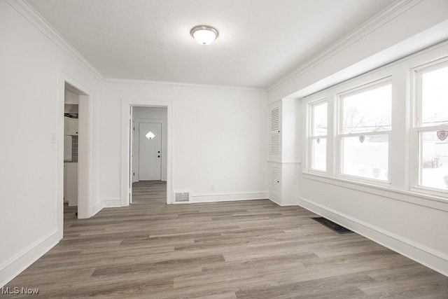 empty room featuring ornamental molding and hardwood / wood-style floors