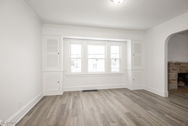 spare room featuring crown molding, hardwood / wood-style flooring, and a fireplace