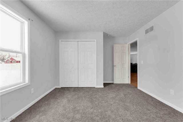 unfurnished bedroom featuring a closet, carpet floors, and a textured ceiling