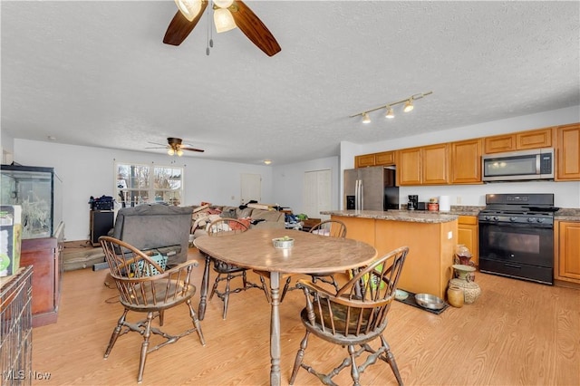 dining area with a textured ceiling, light hardwood / wood-style floors, and ceiling fan