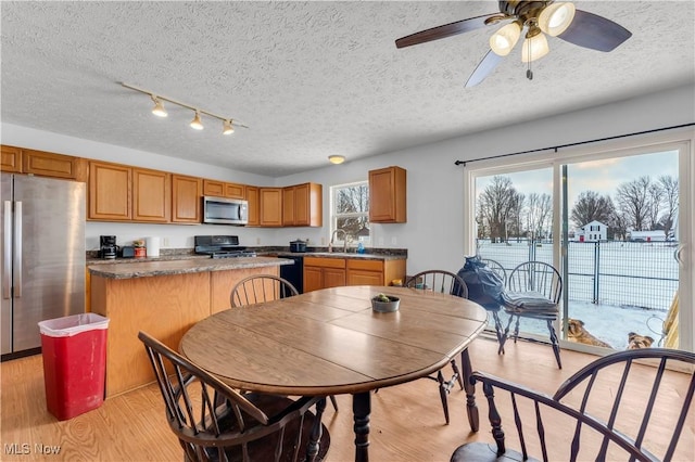 kitchen featuring sink, a textured ceiling, a kitchen island, black appliances, and light wood-type flooring