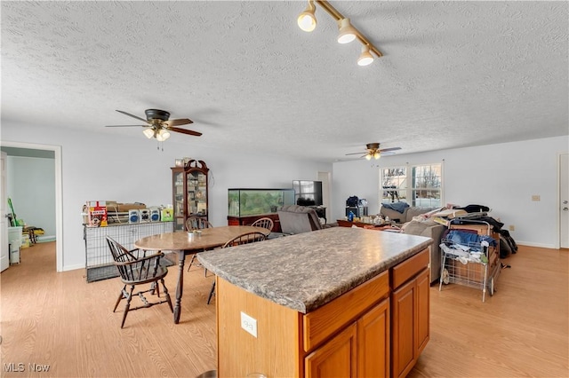 kitchen featuring ceiling fan, a center island, light hardwood / wood-style floors, and a textured ceiling