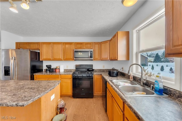 kitchen featuring a textured ceiling, sink, light hardwood / wood-style floors, and black appliances