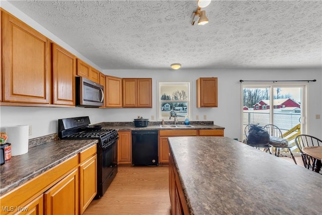 kitchen with light wood-type flooring, a textured ceiling, sink, and black appliances