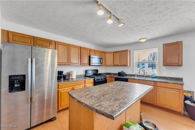 kitchen with sink, rail lighting, light hardwood / wood-style flooring, a kitchen island, and black appliances