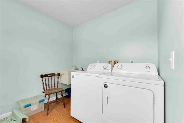 laundry area featuring washer and clothes dryer, light hardwood / wood-style floors, and sink