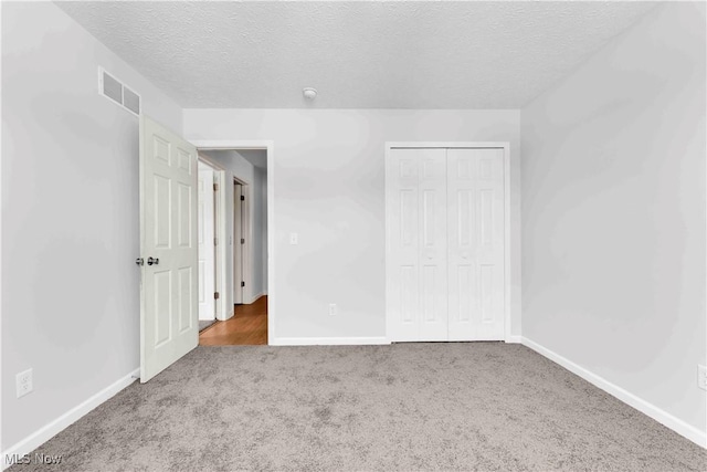 unfurnished bedroom with carpet flooring, a textured ceiling, and a closet