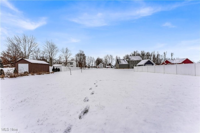 snowy yard featuring a garage and an outdoor structure