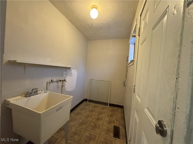 laundry room with a textured ceiling and sink