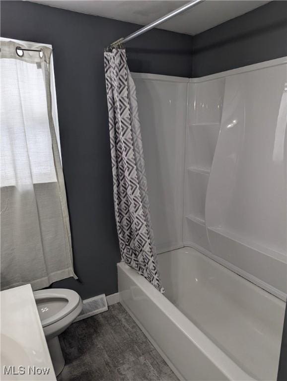 bathroom featuring hardwood / wood-style floors, shower / tub combo, and toilet