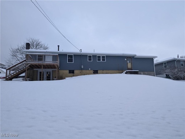 snow covered rear of property with a deck