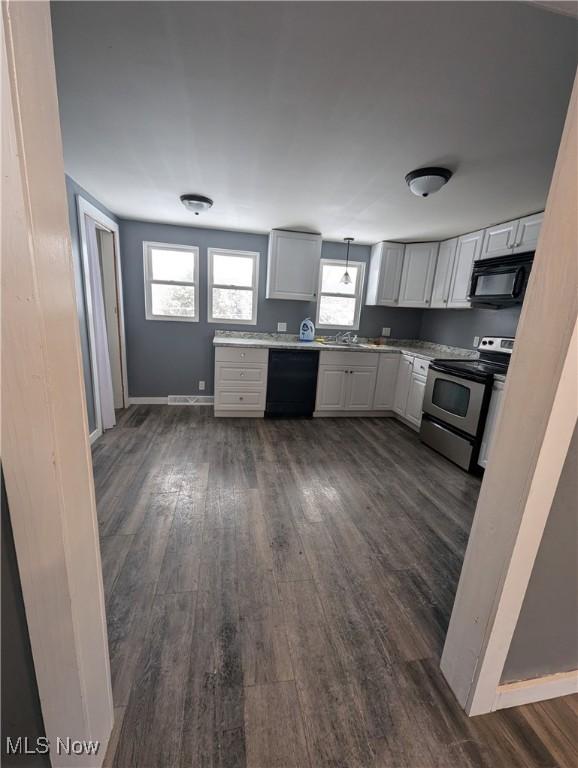 kitchen featuring pendant lighting, white cabinetry, dark wood-type flooring, and black appliances