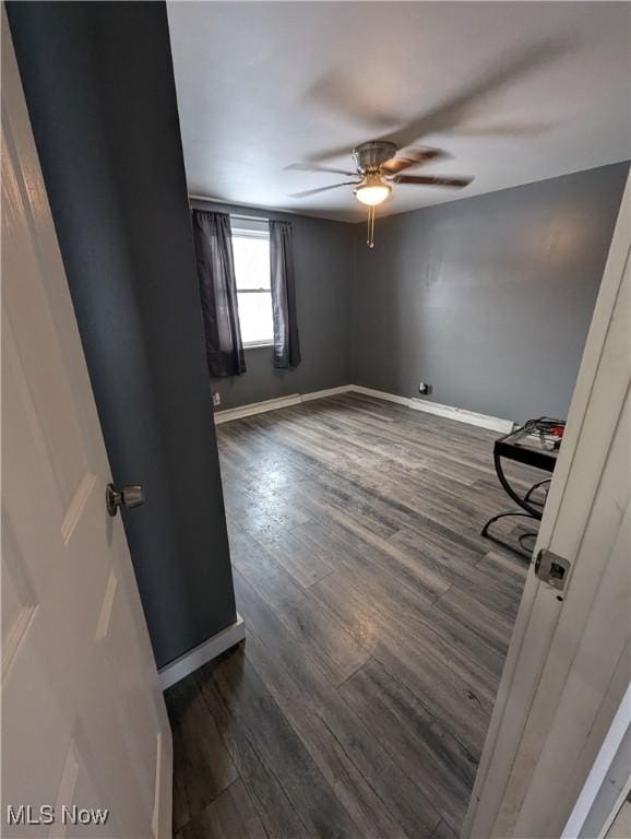 unfurnished room featuring ceiling fan and dark wood-type flooring