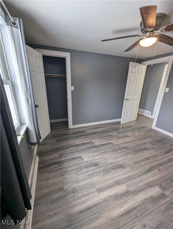 unfurnished bedroom with ceiling fan, dark hardwood / wood-style floors, and a closet