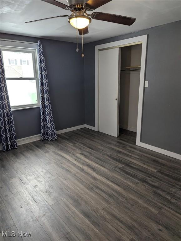 unfurnished bedroom featuring a closet, ceiling fan, and dark wood-type flooring