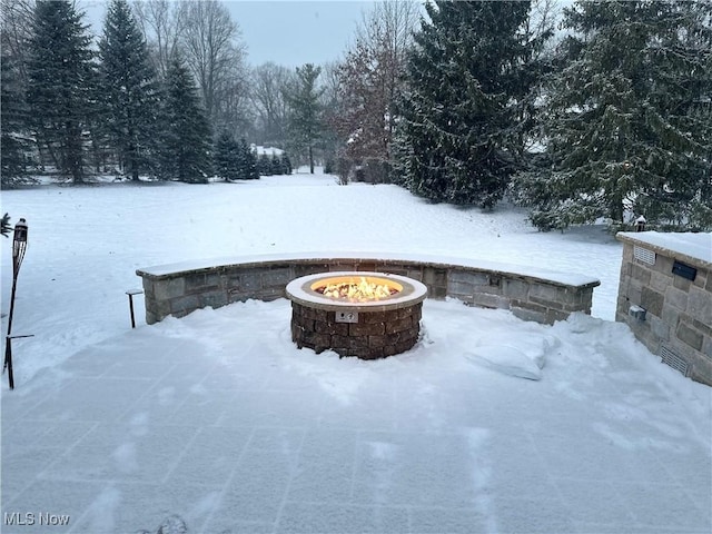 yard layered in snow with an outdoor fire pit