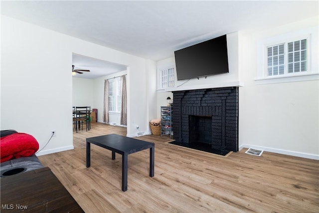 living room featuring hardwood / wood-style floors, ceiling fan, and a brick fireplace