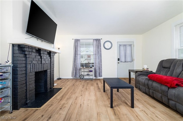 living room featuring light wood-type flooring and a brick fireplace