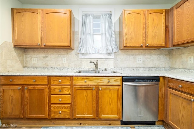 kitchen featuring stainless steel dishwasher, backsplash, light stone counters, and sink