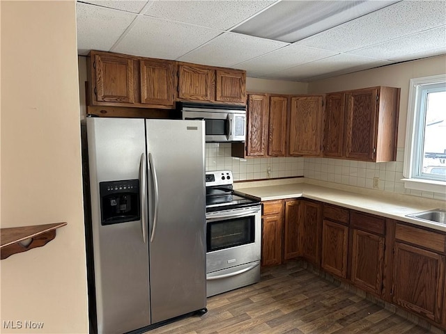 kitchen with decorative backsplash, a drop ceiling, dark hardwood / wood-style floors, and appliances with stainless steel finishes