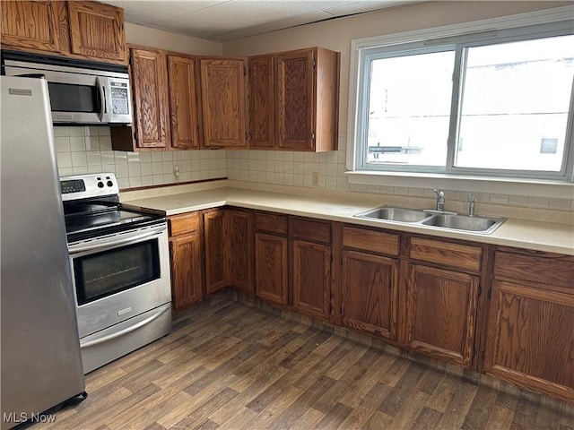 kitchen with dark hardwood / wood-style floors, sink, stainless steel appliances, and tasteful backsplash