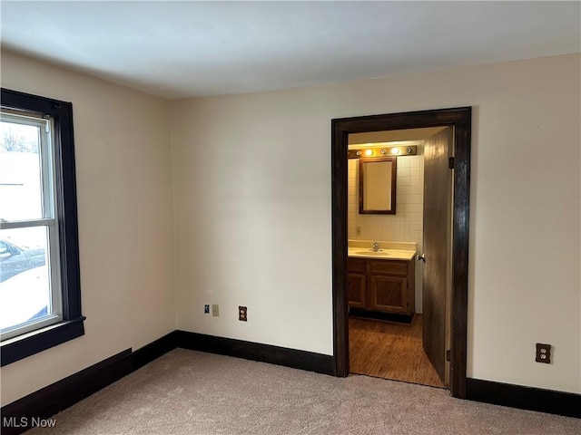 unfurnished bedroom featuring light colored carpet, sink, and connected bathroom