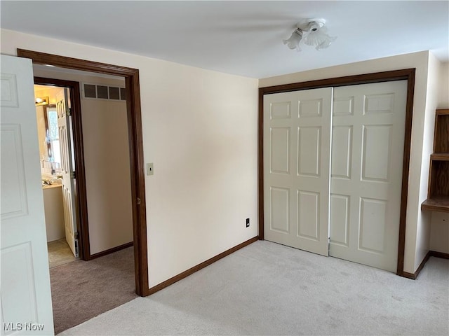 unfurnished bedroom with light colored carpet and a closet