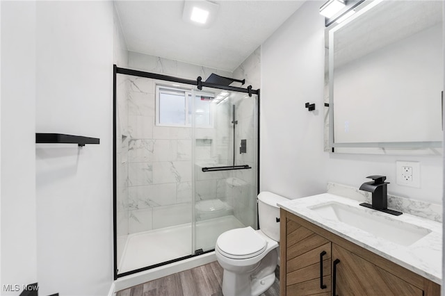 bathroom with a shower with door, vanity, wood-type flooring, and toilet