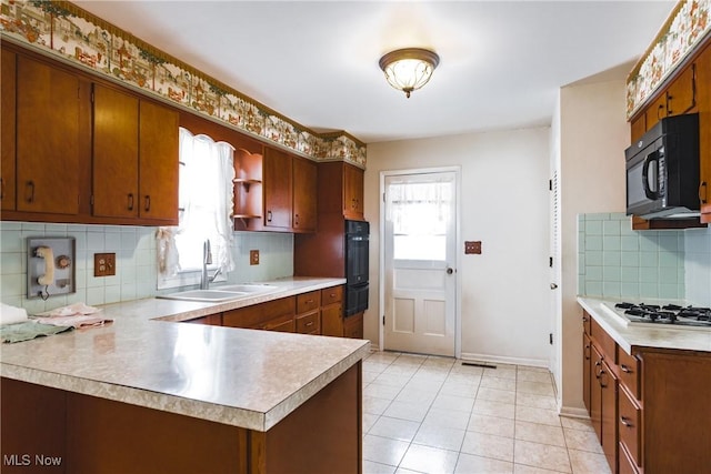 kitchen featuring white gas stovetop, backsplash, sink, a healthy amount of sunlight, and kitchen peninsula