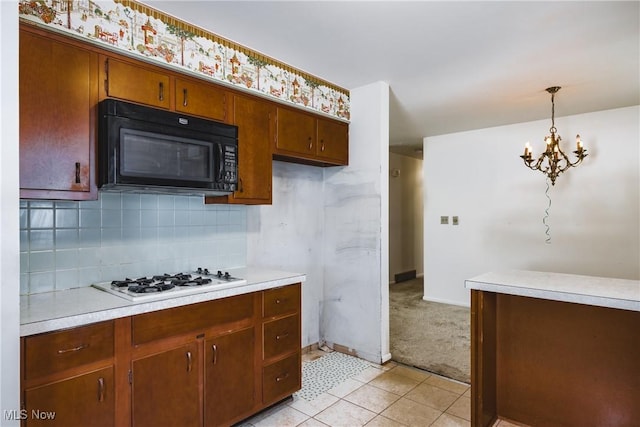 kitchen featuring tasteful backsplash, white gas stovetop, pendant lighting, a notable chandelier, and light tile patterned flooring