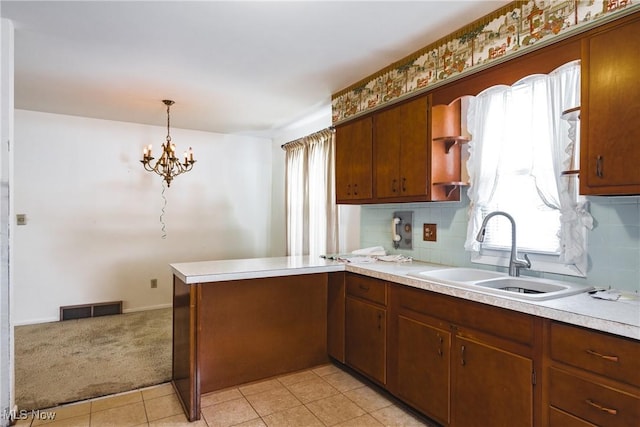 kitchen featuring light carpet, kitchen peninsula, tasteful backsplash, sink, and pendant lighting