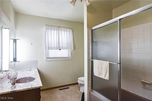 full bathroom featuring vanity, toilet, and bath / shower combo with glass door