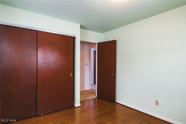 unfurnished bedroom with dark hardwood / wood-style floors and a closet