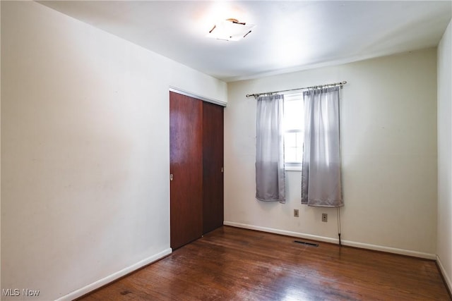 unfurnished bedroom featuring a closet and dark wood-type flooring