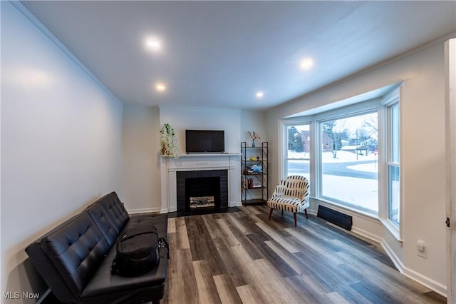 living room featuring dark hardwood / wood-style floors, crown molding, and a brick fireplace