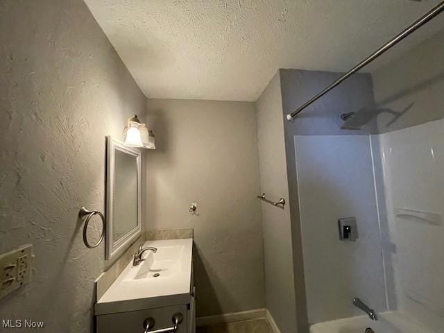 bathroom with vanity, bathing tub / shower combination, and a textured ceiling