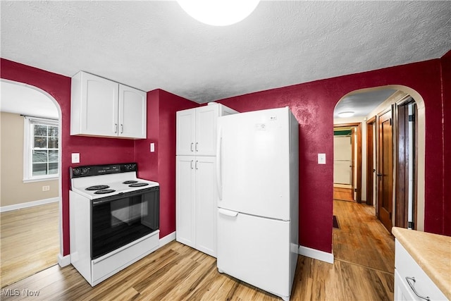 kitchen featuring white cabinets, light wood-type flooring, white appliances, and a textured ceiling