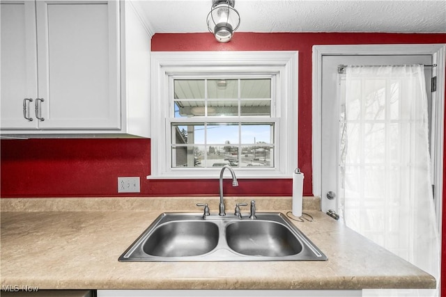 kitchen featuring white cabinetry, sink, and a textured ceiling