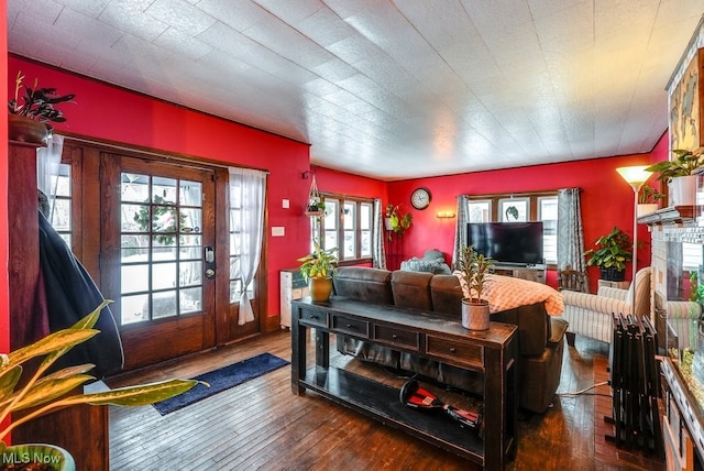 living room with a fireplace, a wealth of natural light, and dark hardwood / wood-style flooring